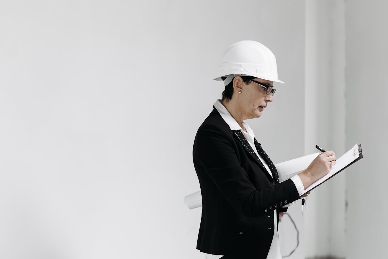 Woman in business attire with hard hat taking notes at a construction site.